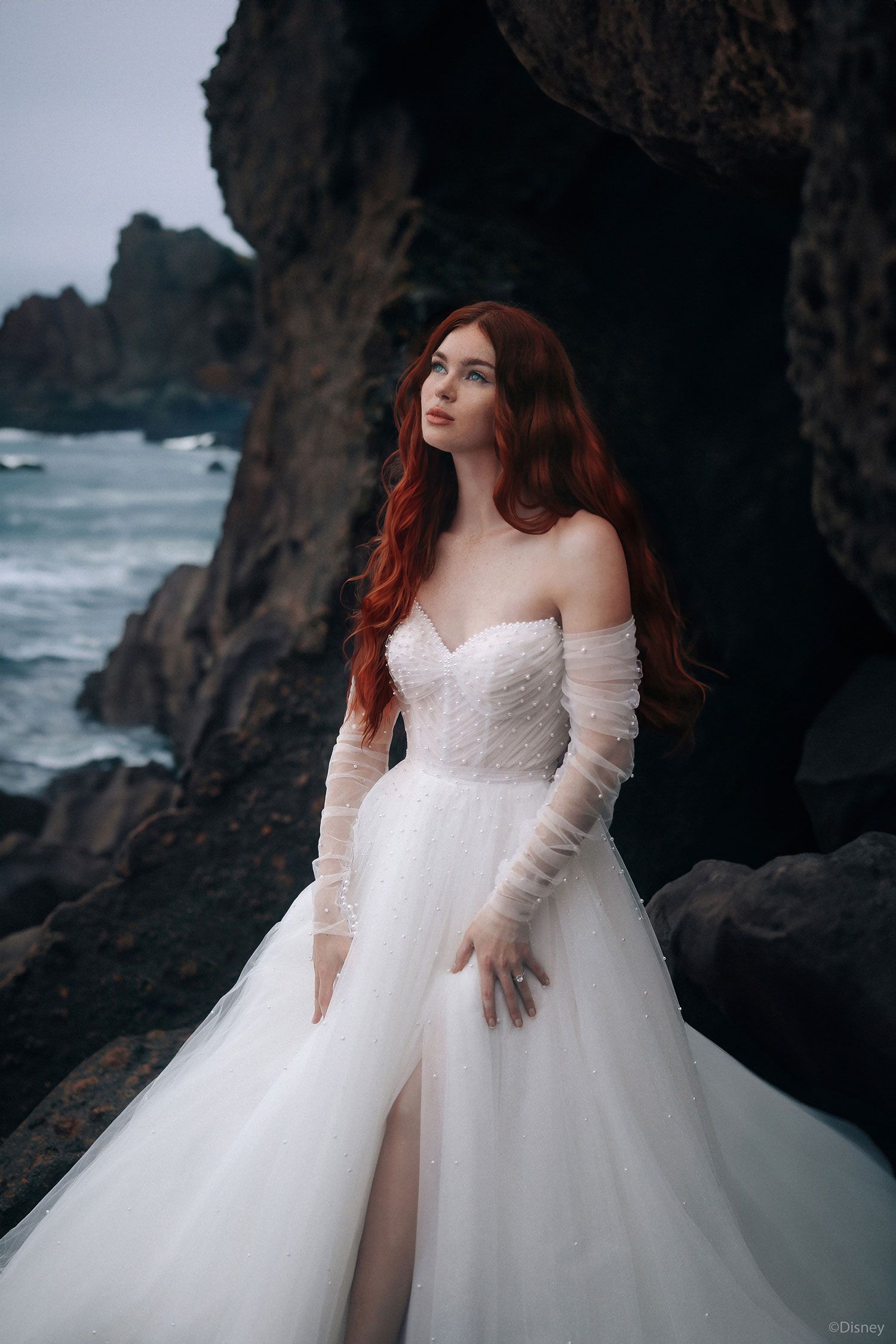 Ariel D440 Wedding dress model on rocks by the sea