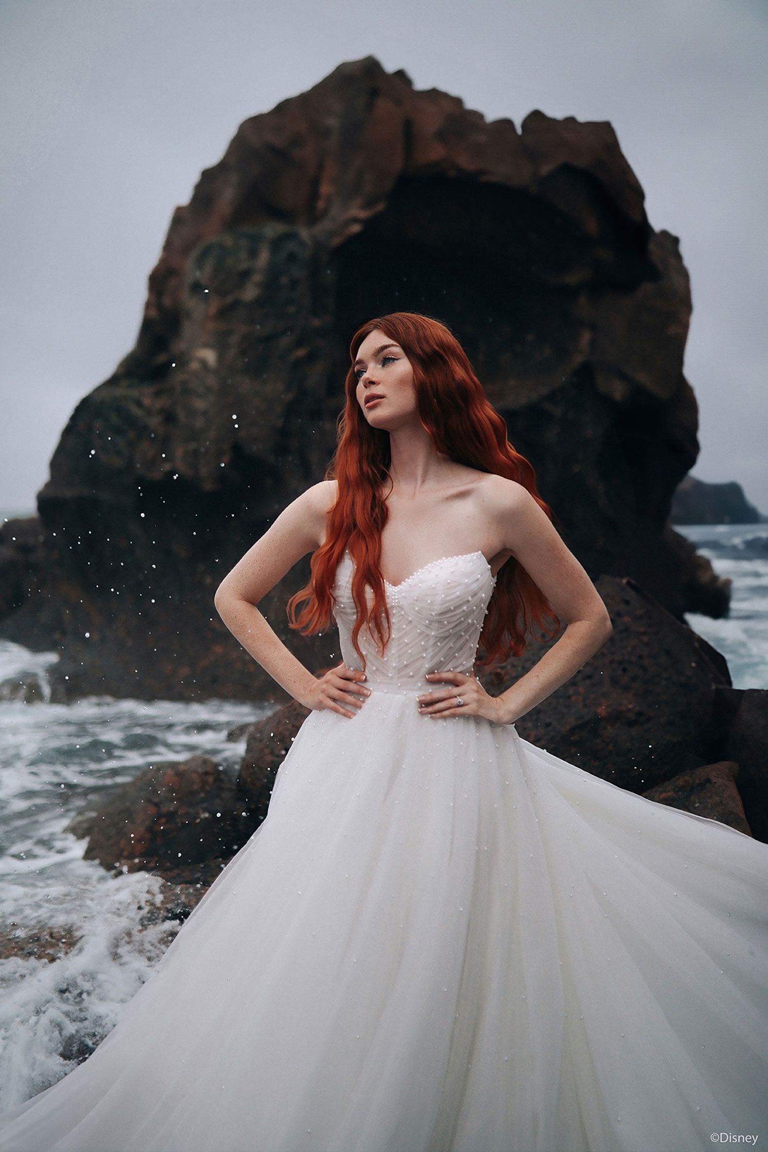Ariel D440 Wedding dress model on rocks by the sea