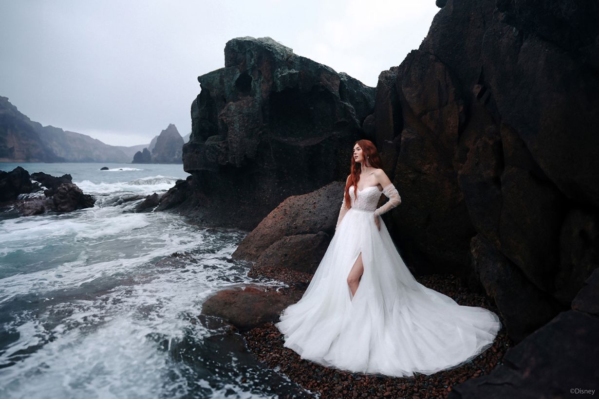 Ariel D440 Wedding dress model on rocks by the sea